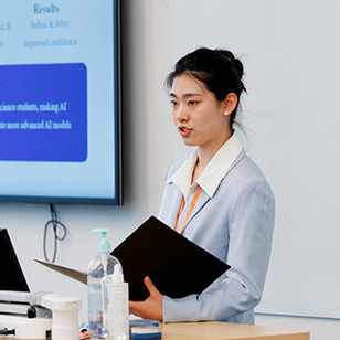 A professional woman giving a talk in front of a class.